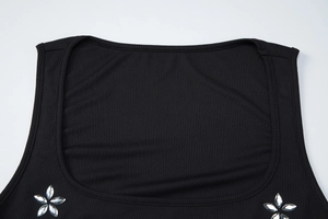 Détail d'un crop top noir en maille côtelée avec fleurs en strass élégantes au décolleté