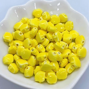 Close-up of yellow shell-shaped ceramic beads for DIY jewelry making in a white bowl