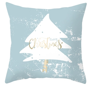 Detail of blue Christmas pillow cover with white tree silhouette and golden Merry Christmas text