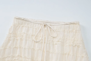 Détail de la texture à volants et du cordon de serrage à la taille de la robe crème