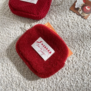 Macro view showing the soft texture of a red plush coin purse with a woven brand tag