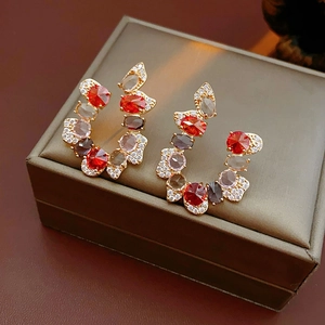 Detailed shot of vintage gold earrings with red and smoke grey zircon stones on brown leather