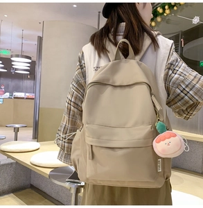 Rückansicht des beigen minimalistischen Rucksacks mit rosa Anhänger im Einkaufszentrum