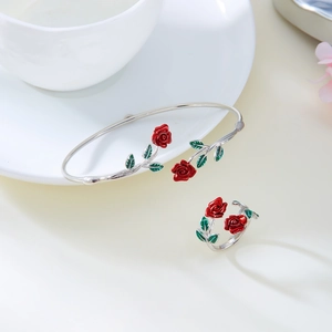 Detail of silver rose bangle and ring set with red enamel flowers on a beige background