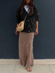 Close-up of a dark grey knit cardigan paired with a white top and brown silk skirt