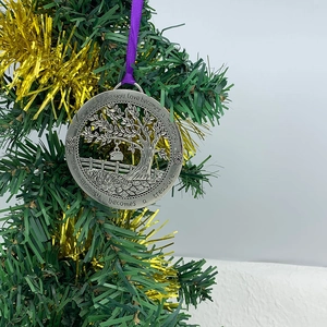 Silver Tree of Life memorial ornament hanging on a Christmas tree with purple ribbon