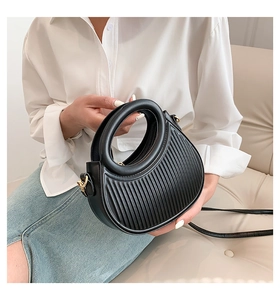 Detail of black pleated PU leather saddle bag featuring a round handle and gold metal hook