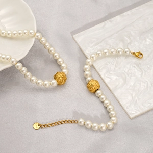 Detail of pearl necklace and bracelet set with S.STEEL tag on gold shell plate