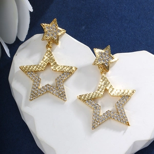 Close-up of gold star earrings with white cubic zirconia on a blue background