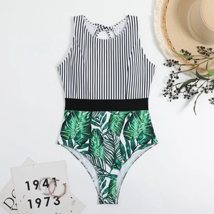 Detail of one-piece swimsuit featuring vertical stripes and tropical leaf print pattern