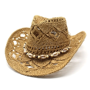 Détail d'un chapeau de cow-boy en paille avec bande de coquillages et perles en bois