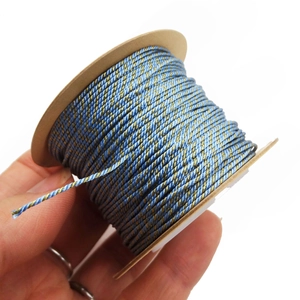Macro detail of blue and gold metallic braided thread wound on a kraft paper spool
