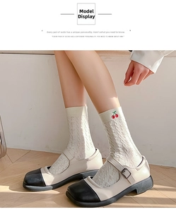 Close-up of beige knit crew socks with embroidered cherry detail and Mary Jane shoes