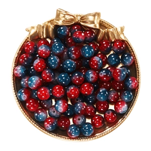 Macro shot of red and blue gradient beads for DIY jewelry in a gold metal tray