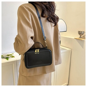 Minimalist black suitcase crossbody bag styled with a beige suit for business look