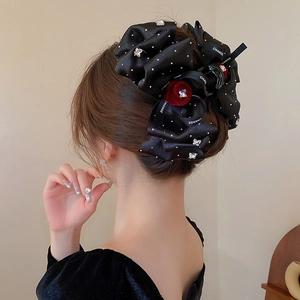 Detailed back view of a large black polka dot bow hair claw clip with a red velvet rose