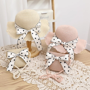 Close-up of kids' straw sun hat and matching bag set with polka dot bows and wavy brims
