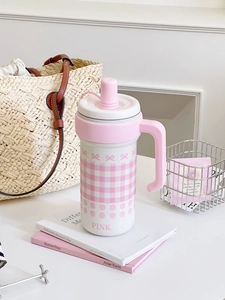 Close-up of pink checkered insulated tumbler with bow design and sturdy handle