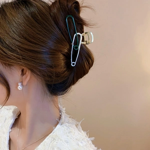 Safety pin hair claw clip in green and white colors holding a twisted hair bun