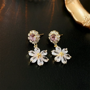 Detailed macro view of gold flower earrings with purple and white zircon crystals