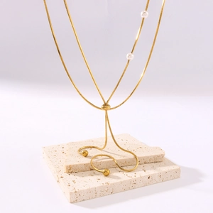 Mehrlagige goldene Schlangenkette mit Perlen und Goldperlen auf einem Steinsockel