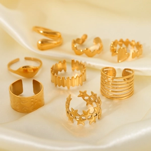 Set of 8 gold minimalist rings including heart and star designs on white silk background