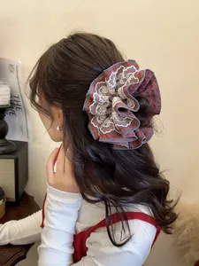Close-up of a large red plaid scrunchie with delicate white lace edges on hair