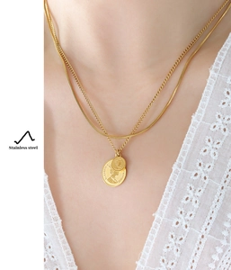 Close-up of a double-layer gold necklace with Queen Elizabeth II coin pendants