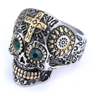 Macro shot of vintage skull ring featuring a gold cross and green gemstone eyes detail