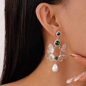 Detail of silver drop earrings featuring green gems, rhinestones, and waterdrop pearls