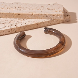 Detailed close-up of brown amber-toned resin cuff bracelet with marble texture