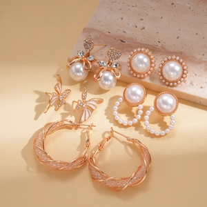 5-pair gold earring set with rhinestones, pearls and butterfly studs on stone background