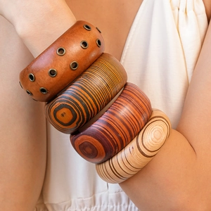 Close-up of stacked wooden bangles featuring natural wood grain and metal rivet details