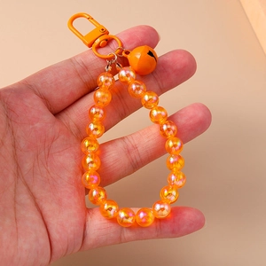 Detail of orange iridescent beaded keychain with a matching small bell and metal clasp