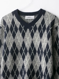 Detailed view of the V-neck and argyle pattern on a gray and navy knit sweater
