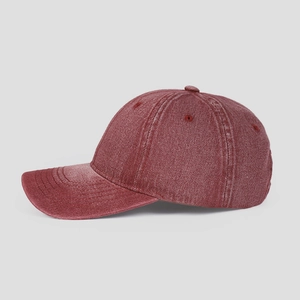 Macro detail of washed burgundy denim fabric and stitching on a six-panel baseball cap