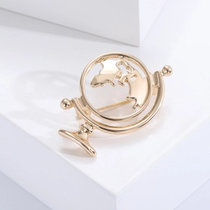Fashionable gold globe brooch made of metal alloy on a minimalist display stand