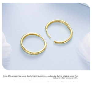 Detail shot of gold S925 sterling silver hoop earrings with star engravings on blue fabric