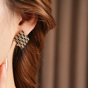 Détails rapprochés des boucles d'oreilles géométriques serties de strass noirs et blancs