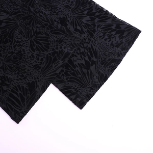 Détail du tissu en maille transparente avec flocage noir aux motifs de papillon et léopard