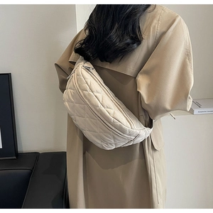 Close-up of beige quilted crossbody bag worn by model in a stylish trench coat