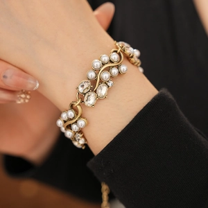 Macro detail of bronze vintage bracelet with white pearls and oval crystals on wrist