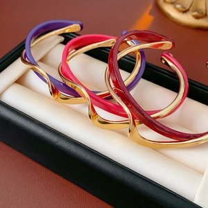 Three-piece set of gold plated wave enamel open bangles in purple, pink and deep red