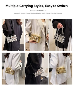Detail shot showing multiple carrying styles and shiny metal beads on a evening clutch bag