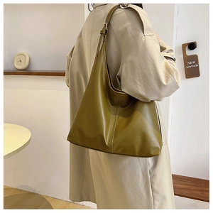 Detailed view of stylish mustard green PU leather tote bag worn by a model in interior