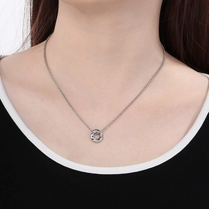 Detailaufnahme des silbernen verschlungenen Ringanhängers mit Kristallen an feiner Kette