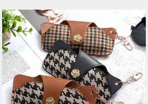 Detail of houndstooth PU leather eyewear pouches with hardware hooks and snap closure