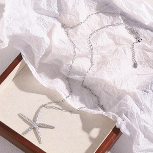 Detail of silver starfish pendant necklace with paperclip chain in a wooden box