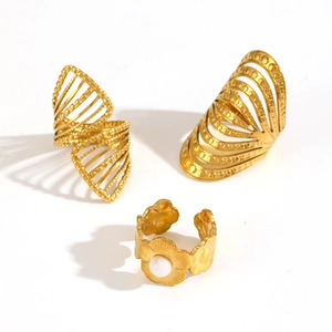 Detail of irregular wave rings and floral gold band with pearl inlay on white background