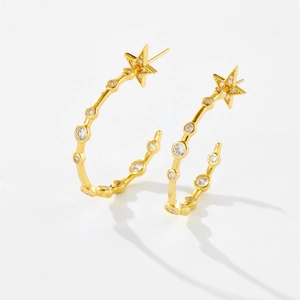 Detail of gold star earrings featuring sparkling white zircon stones and sleek half-hoop